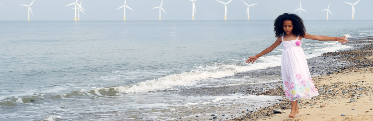 Girl on beach with wind turbines in the background